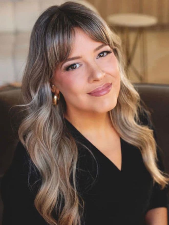 Stephanie Mitchell, smiling, with long blonde waves and a pale cardigan.